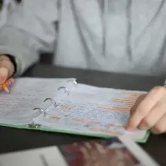 Ręka pisze ołówkiem w zeszycie. Czy to wystarczy, by dostać czwórkę? Od ilu procent jest 4?