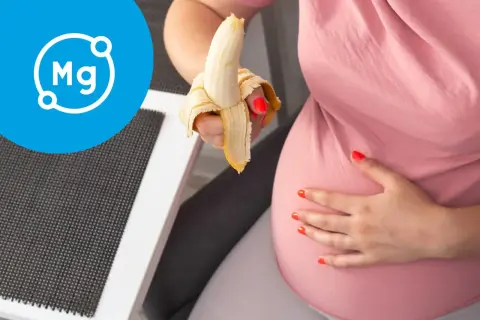 Ciężarna kobieta je banana, symbolizującego magnez w ciąży.