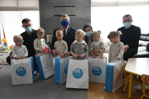 Sześcioraczki w Polsce z rodzicami i wspierającymi ich osobami odbierają prezenty.