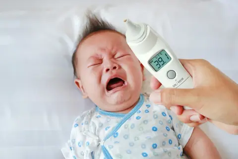 Płacz dziecka i termometr wskazujący 39.1°C. Ewidentna gorączka u dziecka, które nie chce dać się zbadać.