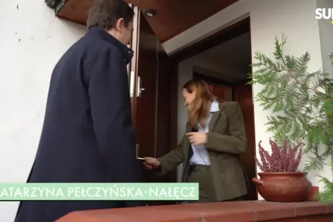 Katarzyna Pełczyńska-Nałęcz otwiera drzwi, a obok stoi mężczyzna.