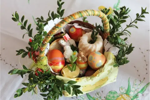 W koszyczku wielkanocnym znajdują się pisanki, babka, chleb, masło i figurki zwierząt. To tradycyjne co wklada sie do koszyczka wielkanocnego.