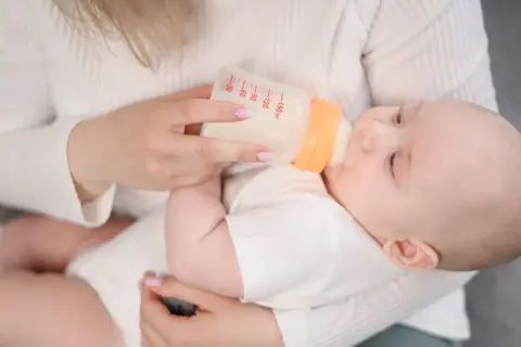 Mama karmi dziecko butelką. Zamiast mleka Bebilon wycofane, używa innego, bezpiecznego dla malucha.