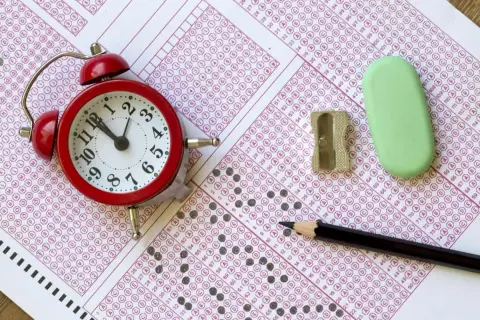 Budzik, ołówek, gumka i temperówka na arkuszu odpowiedzi. Zastanawiasz się, ile trwa egzamin z angielskiego? Czas ucieka!