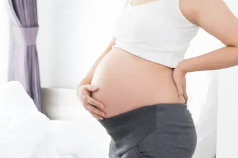 Brzuszek w 21 tygodniu ciąży. Delikatne dotknięcie dłonią, oczekiwanie na maluszka.
