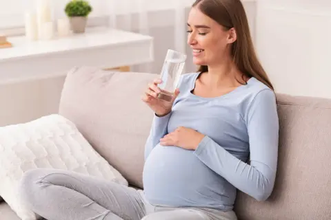 Ciężarna kobieta pije wodę, przygotowując się do testu obciążenia glukozą.