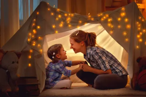 Mama i córka w namiocie z lampek, śpiewają piosenki o mamie.