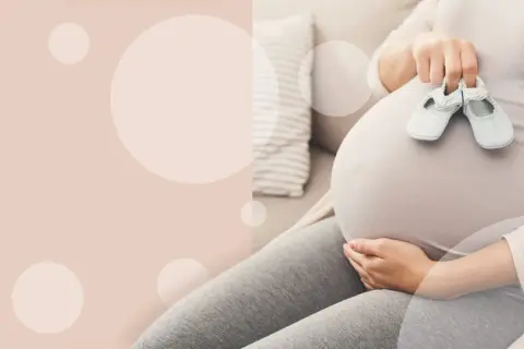 Brzuch ciężarnej kobiety z maleńkimi bucikami. Czas oczekiwania na poród.