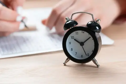 Budzik obok arkusza egzaminacyjnego. Zastanawiasz się, ile trwa egzamin ósmoklasisty? Czas ucieka!