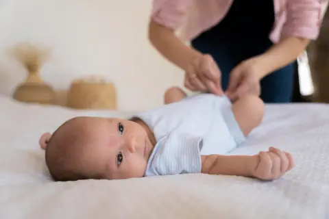 Malutkie dziecko leży na białym tle. Mama przygotowuje się do szczepienia RSV w ciąży, dbając o bezpieczeństwo maluszka.