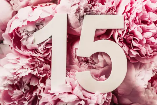 Białe cyfry "15" na tle różowych piwonii symbolizują piętnastą, kryształową rocznicę.