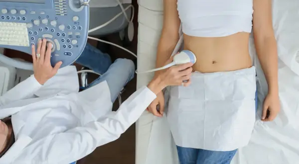 Badanie USG brzucha. Lekarz wykonuje badanie ultrasonograficzne, prawdopodobnie w 12 tygodniu ciąży, sprawdzając rozwój dziecka.