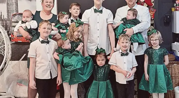 Rodzina z pięcioraczkami w zielonych strojach, pozująca do zdjęcia.