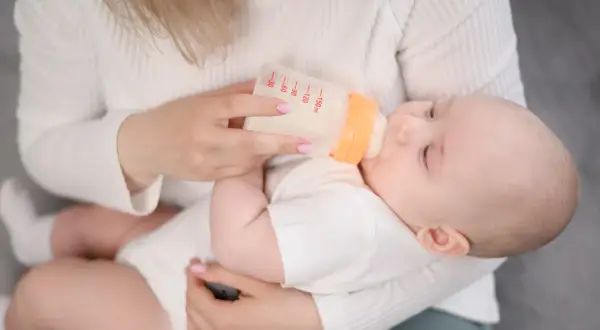 Mama karmi dziecko butelką. Zamiast mleka Bebilon wycofane, używa innego, bezpiecznego dla malucha.