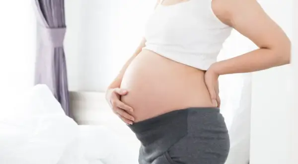 Brzuszek w 21 tygodniu ciąży. Delikatne dotknięcie dłonią, oczekiwanie na maluszka.