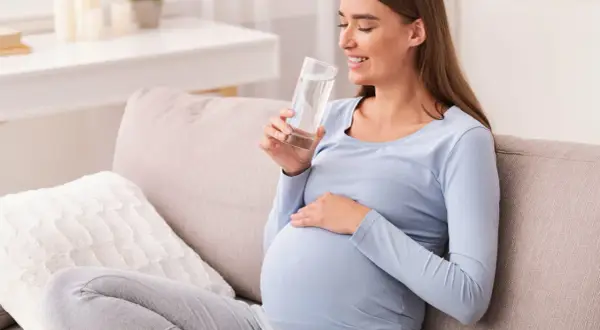 Ciężarna kobieta pije wodę, przygotowując się do testu obciążenia glukozą.