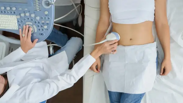 Badanie USG brzucha. Lekarz wykonuje badanie ultrasonograficzne, prawdopodobnie w 12 tygodniu ciąży, sprawdzając rozwój dziecka.
