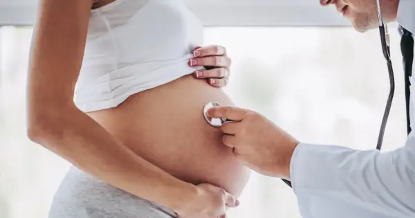 Lekarz osłuchuje brzuch ciężarnej kobiety, która jest w 24 tygodniu ciąży. Słychać bicie serca dziecka.
