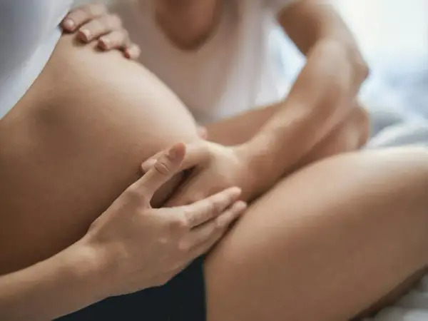 Dłonie obejmujące brzuch ciężarnej kobiety. Czułe dotknięcie, oczekiwanie na narodziny.