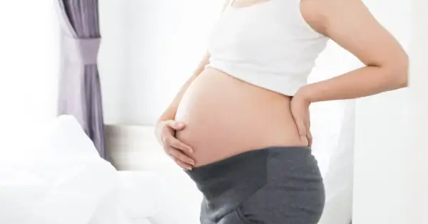 Brzuszek w 21 tygodniu ciąży. Delikatne dotknięcie dłonią, oczekiwanie na maluszka.