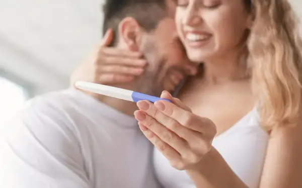 Szczęśliwa para trzyma test ciążowy. Czy jestem w ciąży? Radość i nadzieja w ich oczach.