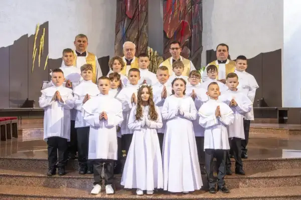 Dzieci w bieli, gotowe na komunię. Zastanawiasz się, ile trwa komunia? To ważny dzień dla tych młodych ludzi.