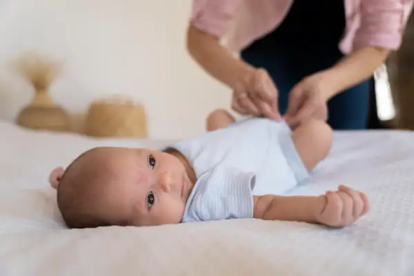Malutkie dziecko leży na białym tle. Mama przygotowuje się do szczepienia RSV w ciąży, dbając o bezpieczeństwo maluszka.